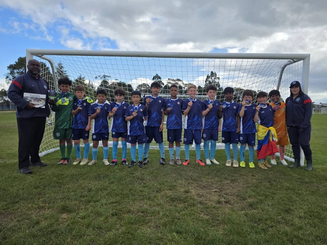 Patagonia FC players and coaches together in front of a football goal, holding their medals